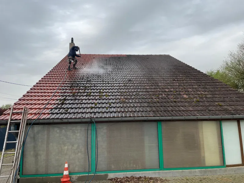 Ouvrier sur le toit au nettoyeur haute pression, moitié propre moitié sale